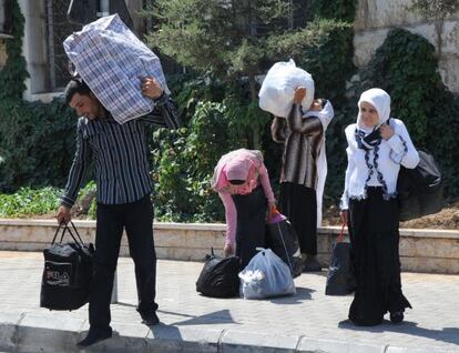Refugiados sirios cargan con sus pertenencias en la frontera de Masnaa, entre Siria y L&iacute;bano. 