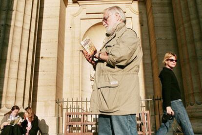 Un turista lee <i>El Código Da Vinci</i> a las puertas de la iglesia de Saint Sulpice en París.