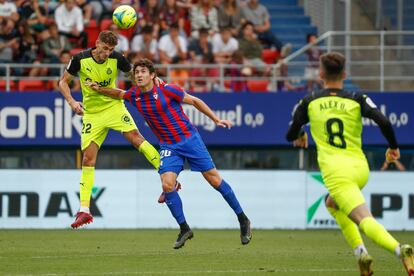 El futbolista del Girona Santi Bueno (I) lucha por el balón con Blanco Leschuk (C), del Eibar, durante el partido de vuelta de la primera eliminatoria de los play offs de ascenso a LaLiga Santander entre el Eibar y el Girona.