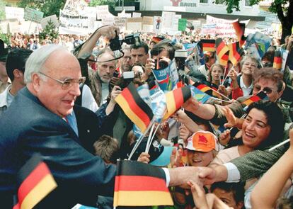 El canciller alemán Helmut Kohl da la mano a sus seguidores mientras que al fondo se ven a agricultores alemanes que protestan contra la política económica de Kohl, en el pueblo de Bad Woerishofen, cerca de Munich, el 15 de julio de 1997.