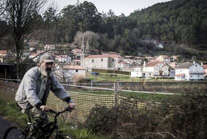 Un vecino de Outes pasa en bicicleta el pasado viernes cerca de la iglesia de Roo.