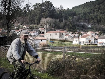 Un vecino de Outes pasa en bicicleta el pasado viernes cerca de la iglesia de Roo.