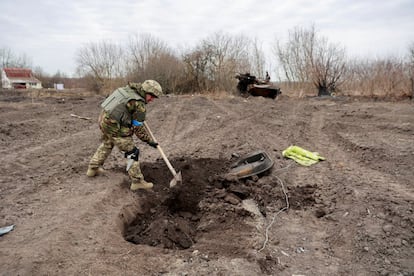 Un militar ucranio entierra los restos del cadáver de un soldado ruso, en el pueblo de Lukianivka, recientemente recuperado por las Fuerzas Armadas de Ucrania. 