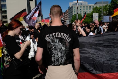 Jóvenes neonazis con banderas alemanas, incluido un joven con una camiseta que dice "Germania", esperan a que la policía les permita reanudar su marcha de protesta el 26 de abril de 2025 en Berlín.