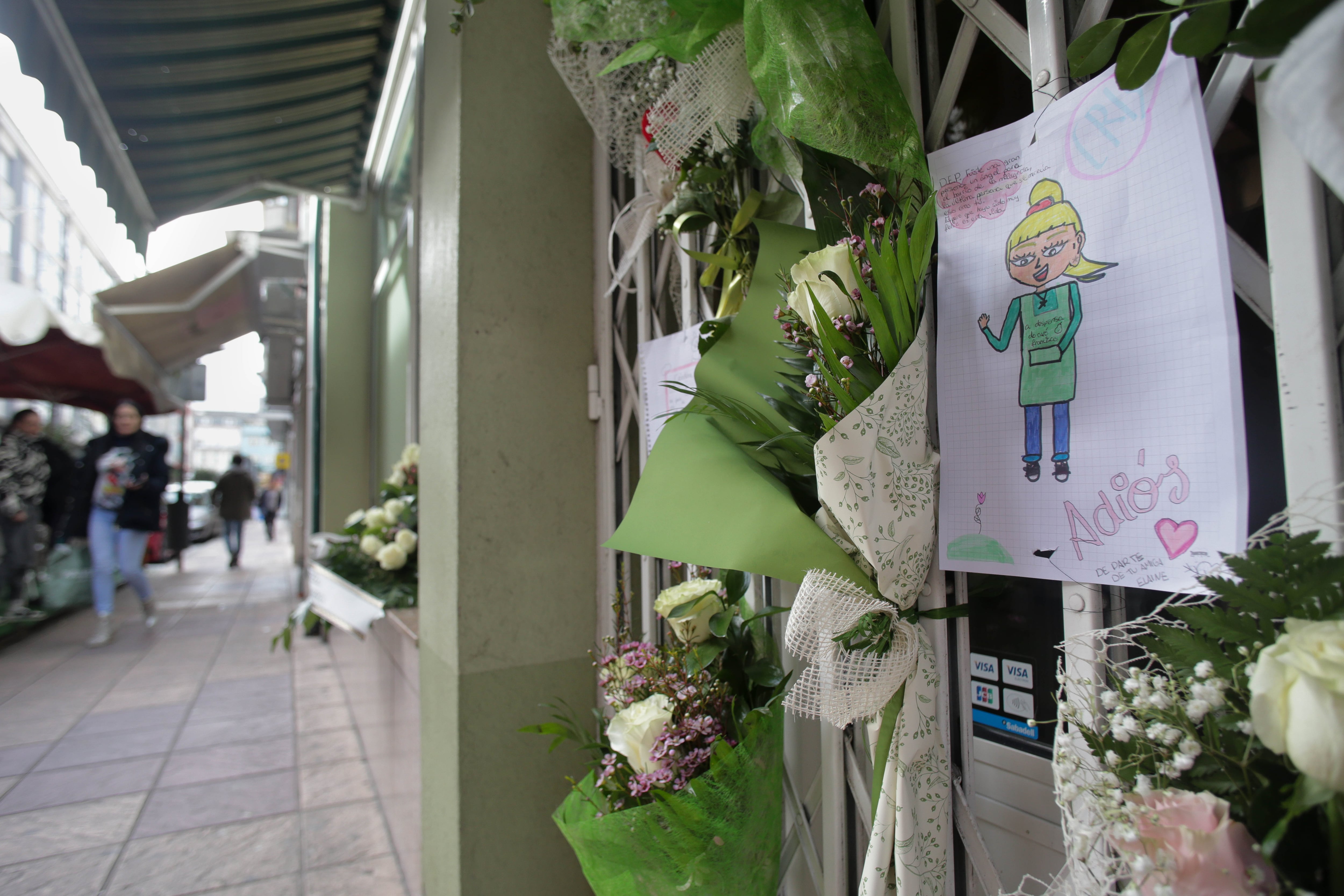 Un dibujo y varias flores colgadas en la tienda de alimentación donde trabajaba la mujer asesinada.