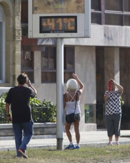 Varios transeúntes fotografían un termómetro este miércoles en San Sebastián.