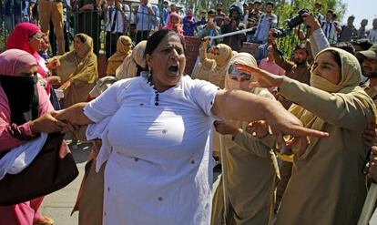Una trabajadora del departamento de asistencia social corea consignas mientras policías indias (d) intentan detenerla durante una protesta en Srinagar, la capital estival de la Cachemira india (India).