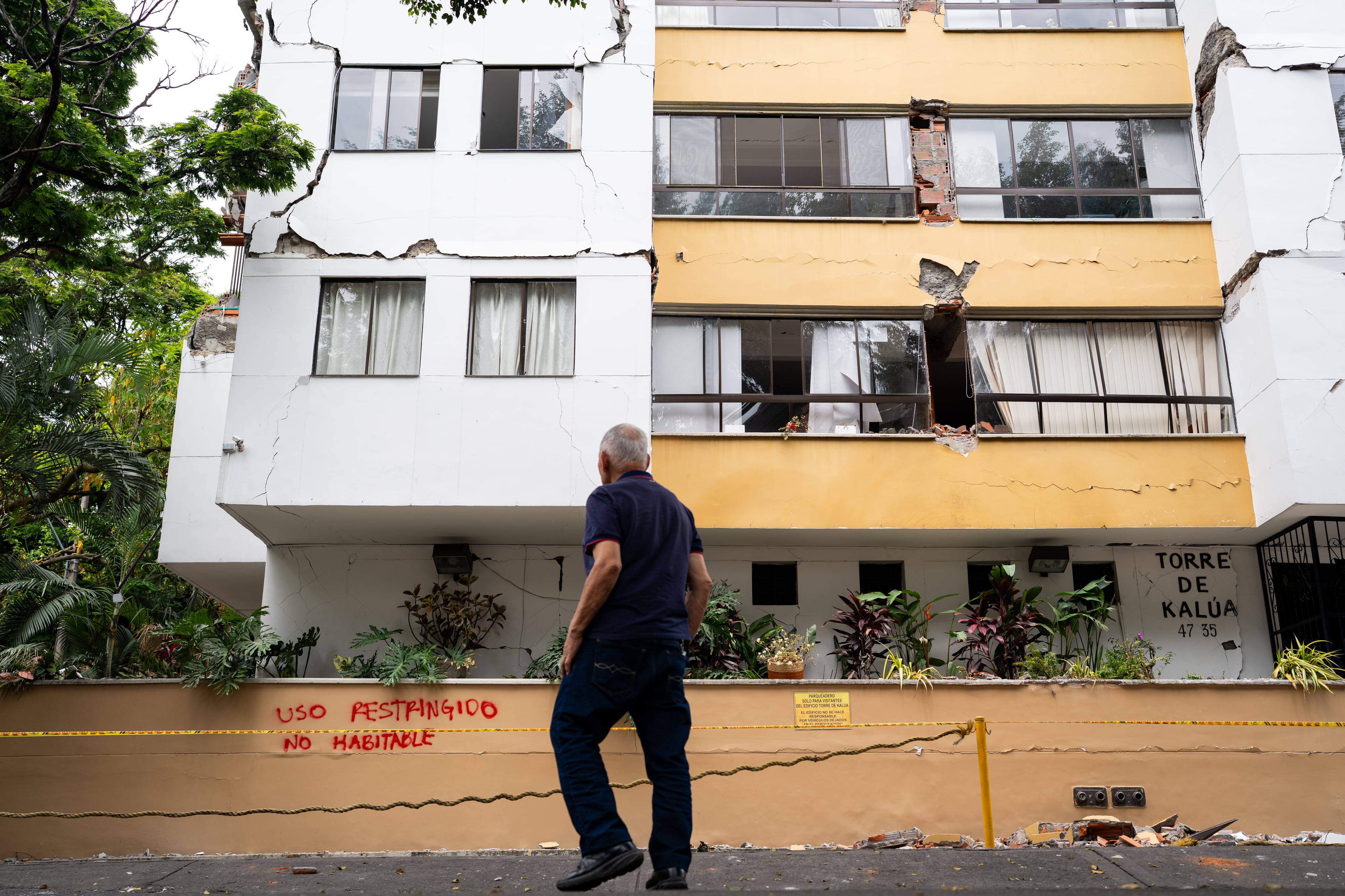 Hebert Sánchez camina en su barrio en medio de edificios afectados, en Cali.
