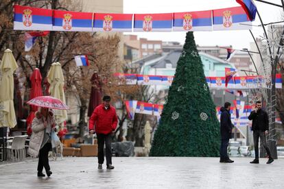 Varias personas caminan en la principal zona peatonal en el norte de Mitrovica, en Kosovo, en la que cuelgan banderas serbias, el 11 de enero.