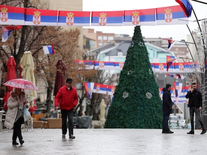 Varias personas caminan en la principal zona peatonal en el norte de Mitrovica, en Kosovo, en la que cuelgan banderas serbias, el 11 de enero.