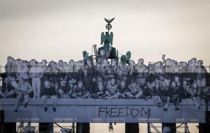 Un collage de fotos del artista callejero y fotógrafo francés, JR, adorna la Puerta de Brandenburgo, en Berlín (Alemania).