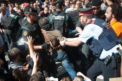 Una persona es agarrada por un miembro de los Mossos y de la Guardia Civil durante una manifestación frente al Departamento de Exteriores.