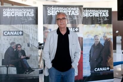 El escritor Juan José Millás junto a carteles del programa de entrevistas <i>Conversaciones secretas</i>, que se emitirá en Canal+.