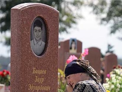 Una mujer llora junto a la tumba de una víctima de Beslán.