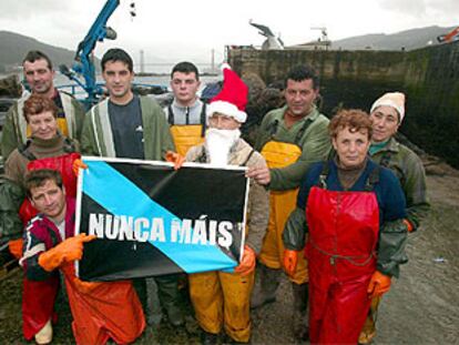 Vecinos de Domaio (ría de Vigo), en el puerto junto a un cartel de Nunca Máis.