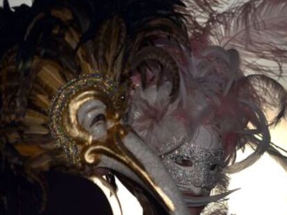 Una pareja portando espectaculares máscaras pasean por Venecia