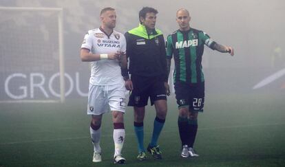 El árbitro Domenico Celi habla con los capitanes del Torino (Paolo Cannavaro, a la izquierda) y del Sassuolo (Kamil Glik) antes de suspender el partido por niebla.