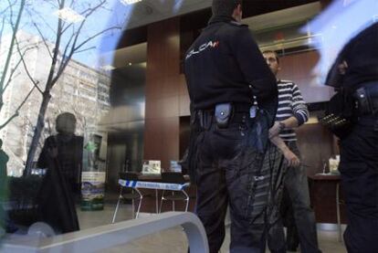Dos policías nacionales, dentro de la sucursal de Caixa Penedès atracada ayer.