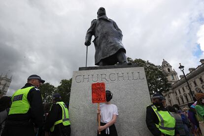 Agentes de policía custodian una estatua de Winston Churchill mientras un manifestante sostiene un cartel en el que se puede leer: "¡Enseñen la historia colonial en el colegio!", en Londres, el pasado 27 de junio.