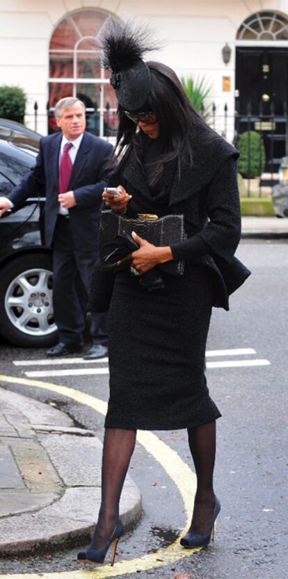 Naomi Campbell mira su teléfono a la llegada al funeral. La modelo rindió un homenaje a Alexander McQueen en un desfile benéfico que organizó a favor de Haití. Ella se subió a la pasarela, acompañada de Kate Moss, con algunos de los últimos diseños de McQueen. En el caso de Moss no pudo contener las lágrimas al recordar a su amigo.