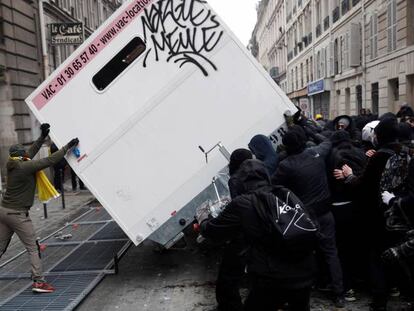 Manifestantes en París vuelcan un contenedor durante la manifestación en contra de la reforma de las pensiones del gobierno de Emmanuel Macron.