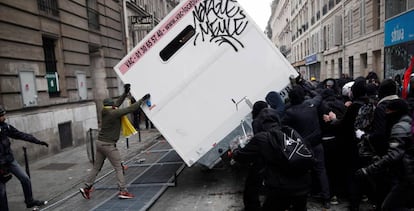 Manifestantes en París vuelcan un contenedor durante la manifestación en contra de la reforma de las pensiones del gobierno de Emmanuel Macron.