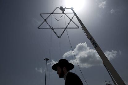 Un judío ultraortodoxo pasa debajo de un adorno con forma de estrella de David. Operarios preparan las calles de Jerusalén para la celebración del Día del Recuerdo de los Soldados Caídos de Israel el próximo 22 de abril.