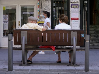 Una pareja de ancianos con mascarilla sentada en un banco, en Madrid.