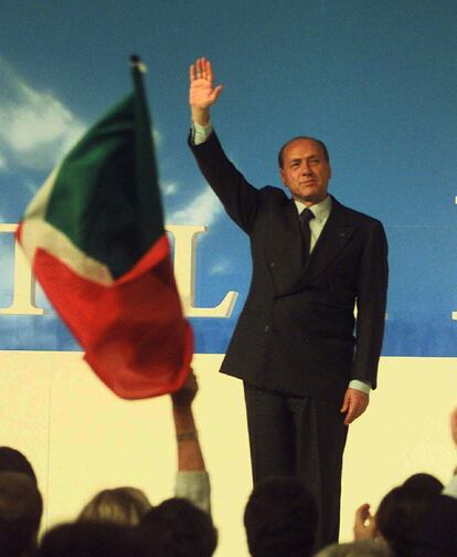 El ex primer ministro italiano y magnate de los medios de comunicación, Silvio Berlusconi saluda a los seguidores después de haber sido elegido de nuevo como presidente del partido Forza Italia, durante un mítin en Milan, el 18 de abril de 1998.