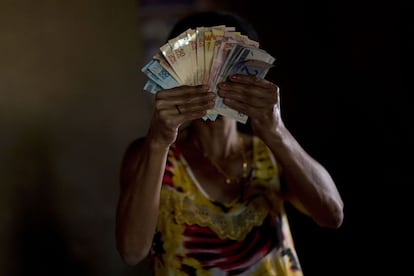 Sueli Paes Alecrin, de 48 años, sujeta su sueldo mensual en Aguas Lindas, cerca 50 kilómetros de Brasilia (Brasil). Su hija Amanda Suellen Lima, de once años, padece una parálisis cerebral. Sueli cuenta con un salario mínimo de 222 euros, dinero público que recibe por la enfermedad de su hija como parte de un programa gubernamental.