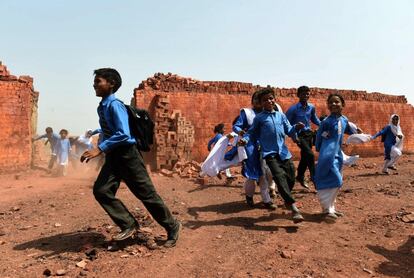 Niños paquistaníes van de camino a casa tras acudir a la escuela en las afueras de Lahore, ciudad de Pakistán.