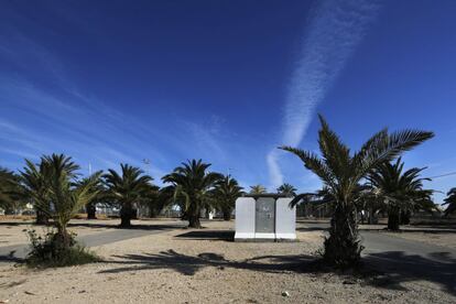 Refugio de hormigón blanco rodeado de palmeras en el aparcamiento de una univerdisad.