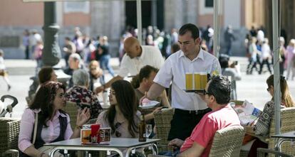 Un camarero sirve bebidas en una terraza en la plaza de la Virgen de Valencia. 