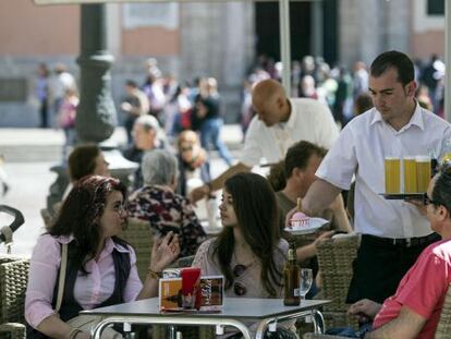 Un camarero sirve bebidas en una terraza en la plaza de la Virgen de Valencia. 