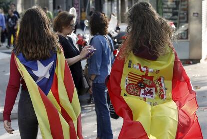 Dos personas con dos banderas distintas caminando juntas.