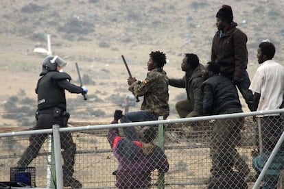 Enfrentamiento entre los agentes antidisturbios y los inmigrantes encaramados a la valla fronteriza de Melilla tras el salto de este jueves. Los subsaharianos han intentado quitarles las defensas a los guardias y se han apoderado de algunos de sus cascos y porras, mientras estos trataban de hacerles bajar.