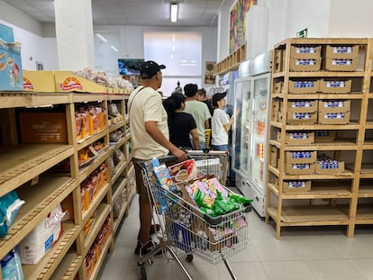 Beneficiarios de la Fundación Alberto y Elena Cortina esperan su turno para canjear alimentos por puntos, el pasado 2 de julio en Madrid.