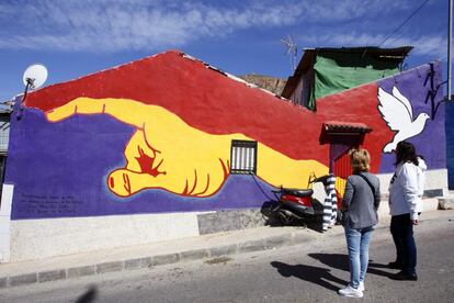 Dos personas se paran a observar uno de los murales de Orihuela dedicados al poeta Miguel Hernández, nacido en esta localidad en 1910. El mural pintado con los colores de la bandera republicana homenajea el activismo político del poeta, quien se alistó en el bando republicano, llegando a recitar sus poemas en la radio para animar a sus compañeros de trinchera.