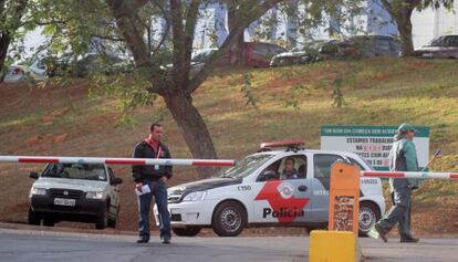 Policial e funcion&aacute;rios na frente da f&aacute;brica assaltada, em Campinas.