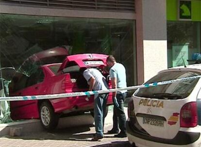 Dos policías registran el BMW que fue empotrado contra el escaparate de Caja Madrid.