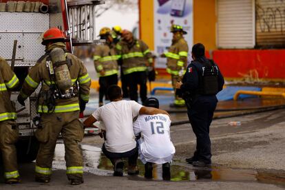 Dos familiares de una de las víctimas del ataque a la tienda de conveniencia se abrazan luego de que los bomberos lograran sofocar el fuego.