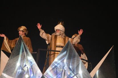 El rey Melchor saluda desde su carroza, acompañado por sus pajes.