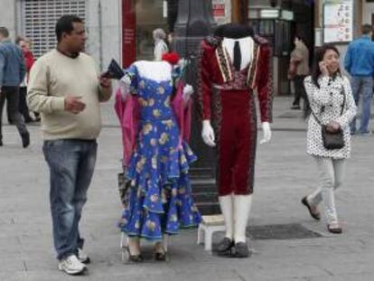 Un vendedor trata de llamar la atención de los turistas, en la Puerta del Sol de Madrid, para que adquieran fotografías con los "trajes típicos" que ofrece. EFE/Archivo