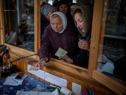Mujeres ucranias muestran su identificación dentro de una iglesia para recibir ayuda humanitaria en Bucha, en las afueras de Kiev, este martes.