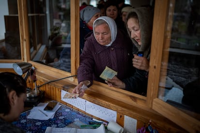 Mujeres ucranias muestran su identificación dentro de una iglesia para recibir ayuda humanitaria en Bucha, en las afueras de Kiev, este martes.