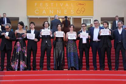 El director brasileño Kleber Mendonca Filho y el elenco de la película "Aquarius" sostienen carteles que rezan "Brasil experimenta un golpe de estado" en el Festival de Cine Internacional de Cannes.