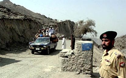 Un soldado paquistaní vigila la frontera, a la que se acerca un coche cargado de refugiados afganos.