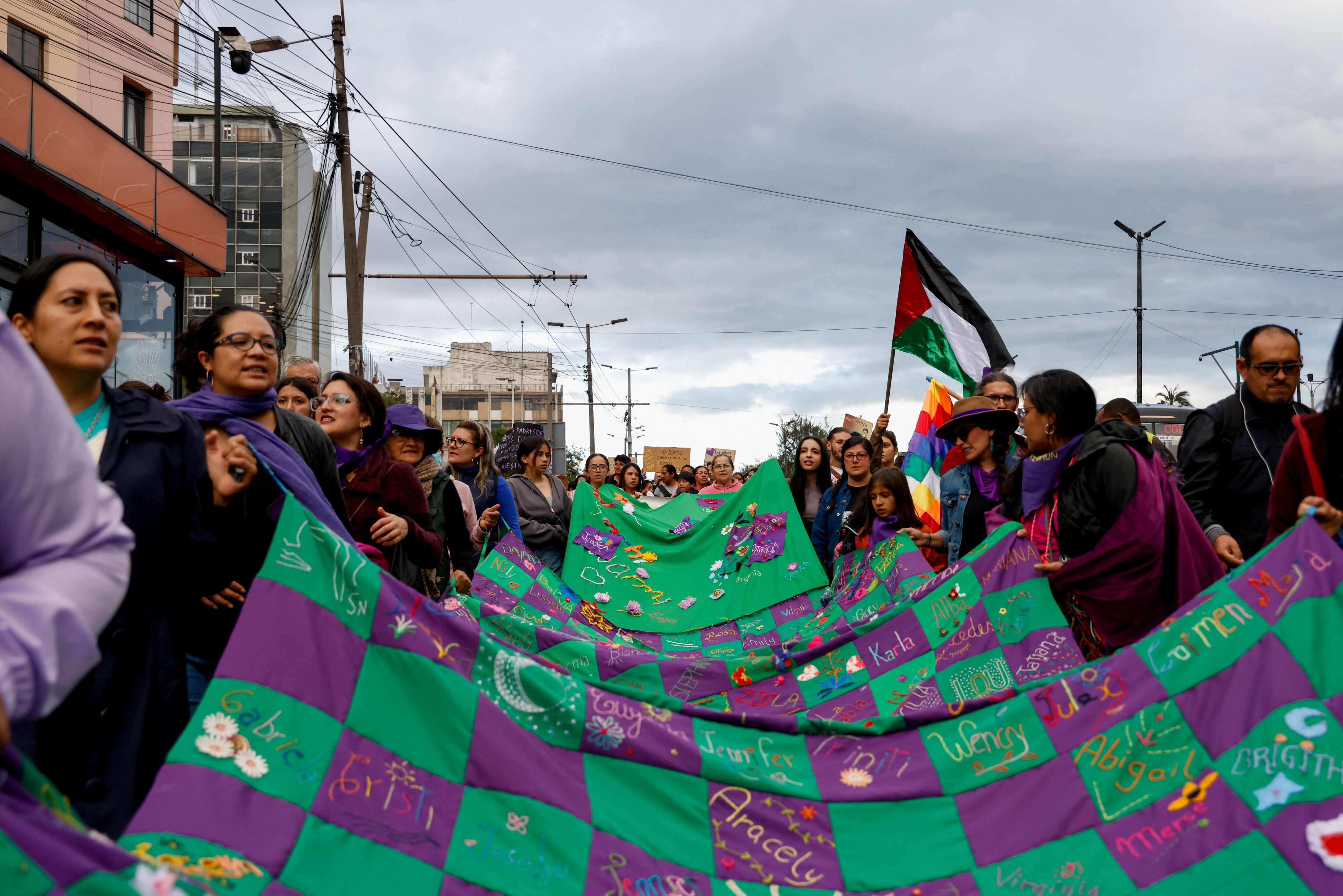 Mujeres llevan un textil verde y morado durante la marcha del Día Internacional de la Mujer en Quito, el 8 de marzo.