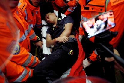 Médicos intentan sacar a un hombre herido durante una manifestación masiva en el aeropuerto internacional de Hong Kong (China).