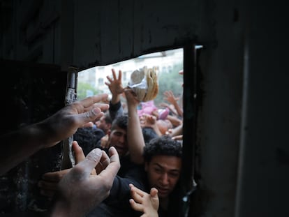 Palestinos desplazados se asoman a la ventana de una panadería para intentar conseguir pan en el campo de refugiados de Nuseirat (Gaza), este jueves.